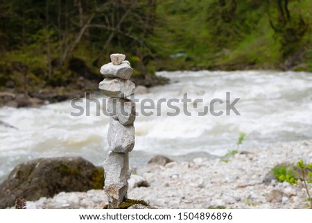 Cairn, stone sculpture, against the mountain river water. White stones of the pyramid in the forest symbolizing zen, harmony, balance.