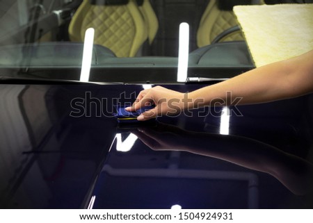 Car Detailing - A man is applying a nano protective coating to a car. A professional ceramic stacker applies different layers to the machine with an applicator sponge. Concept from: Auto Detailing Royalty-Free Stock Photo #1504924931