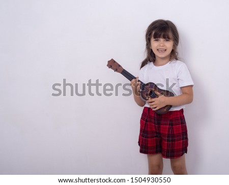 Funny kid girl with guitar, ukulele guitar. Fashionable country girl playing music. 