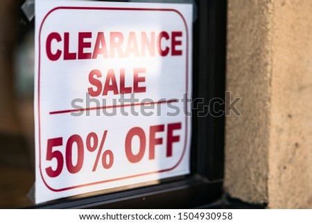 Store shop with clearance sale 50 percent off sign on glass window door entrance in shopping mall or street