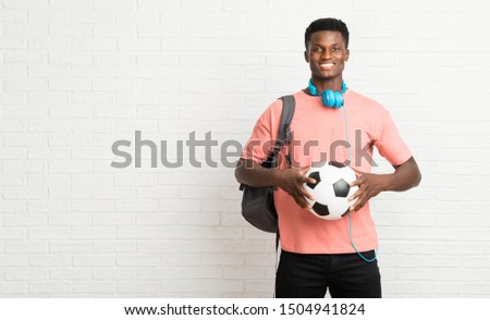 Young afro american man student holding a soccer ball