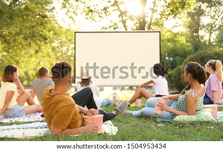 Young people watching movie in open air cinema. Space for text Royalty-Free Stock Photo #1504953434