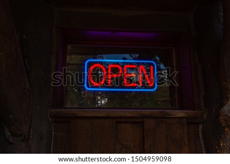 Neon Open sign light on dark old wooden door . Night frame light decoration. Glowing shining neon design element. Entrance neon Open light for bar, club.