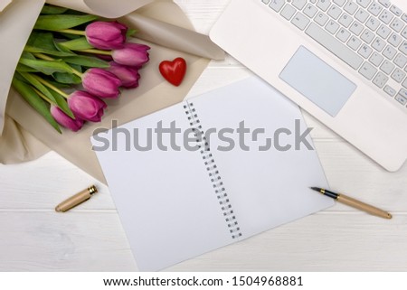 Office desk and bouquet of tulips top view