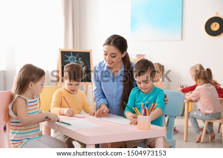 Little children with kindergarten teacher drawing at table indoors. Learning and playing Royalty-Free Stock Photo #1504973153