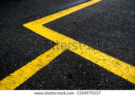 Vivid yellow lines on black surface, road signage abstract elements.