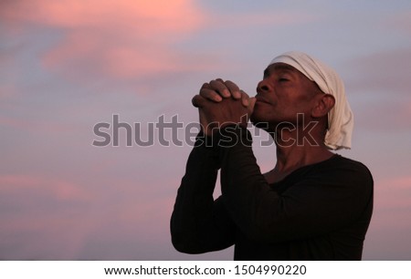 black man praying to god with arms outstretched looking up to the sky stock photo