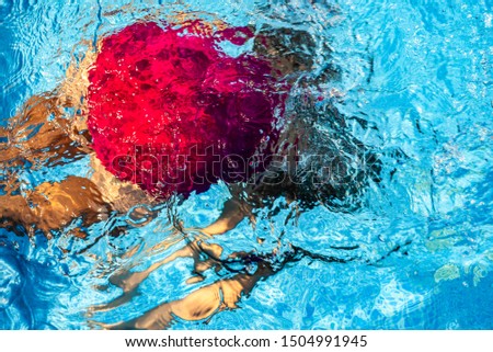 Young girl skilfully swimming in the pool.   Joyful kid's fun in the transparent blue water.  Additional activities for the child. Relaxing in the swimming pool. Leisure.