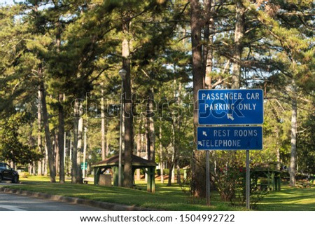 Rest area by highway road in Alabama with rest area sign, passenger car parking only and restrooms with telephone at visitor center in Lanett, Alabama