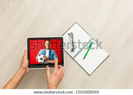 Hand holding tablet with soccer ball flying off screen