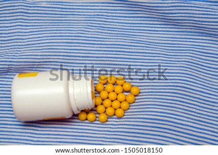 yellow pills and pill bottle on blue background