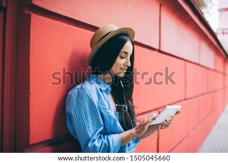 Young millennial hipster girl taking rest at urban city for listening favourite music podcast spending free time for installing application with audio books, concept of generation z lifestyle