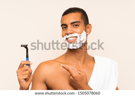 Young handsome man shaving his beard over isolated background and pointing it