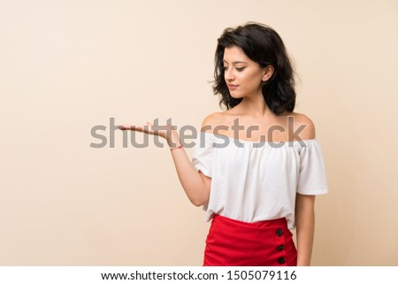 Young woman over isolated background holding copyspace with doubts