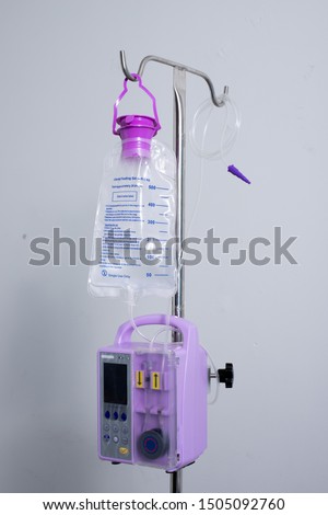 Feeding Pump medical device purple color to supplement nutrition liquid food to tube Enteral feeding fluid set bag with clamp hanging on stand. Royalty-Free Stock Photo #1505092760