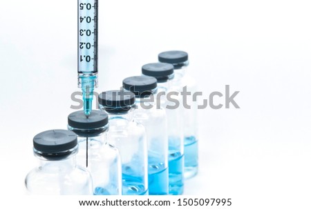 Close up of syringe and serial medicine vials containing blue liquid medicine on the white background Royalty-Free Stock Photo #1505097995