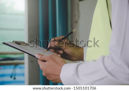 Construction. young foreman builder, engineer or inspector checking and inspecting with clipboard at construction site building interior before complete new project, contractor and engineering concept Royalty-Free Stock Photo #1505101706