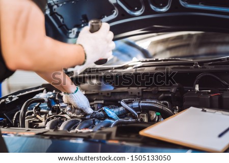 Mechanic man examining and maintenance to customer the engine a vehicle car hood, Safety inspection test engine before customer drive on a long journey, transportation repair service center Royalty-Free Stock Photo #1505133050