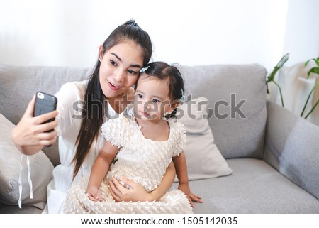 Asian mother are using cell phones take selfie photo with her daughter. The love of a mother with a daughter.
