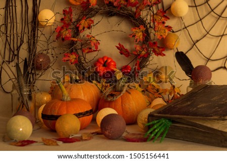 Halloween decoration of pumpkins, autumn wreath with yellow leaves, spell books and garlands.