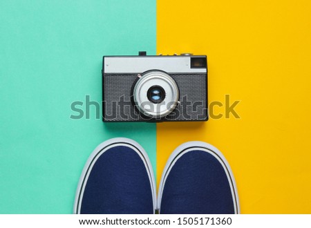 Hipster style flat lay. Classic sneakers and retro film camera on a pastel colored background. Top view
