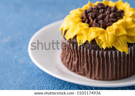Beautiful sunflower decorated chocolate cupcake on blue background