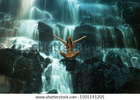 natural portrait of young beautiful and happy Asian Korean woman in bikini enjoying nature at tropical paradise waterfall with magical feeling in travel destination and soul inspiration concept