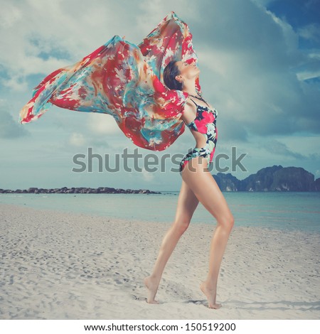 Luxurious woman in color dress on the beach