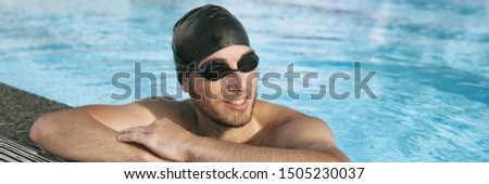 Swimmer athlete man wearing sport goggles and swim cap in indoor swimming pool portrait panoramic banner crop. Portrait of sporty active person lifestyle.