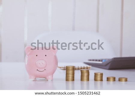 Piggy and coins and calculator on a pile of money saving on wooden table. Business financial concept