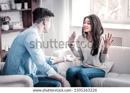 Expressively gesturing. Swearing couple having quarrel about their life together and woman raising her hands in strong gesture