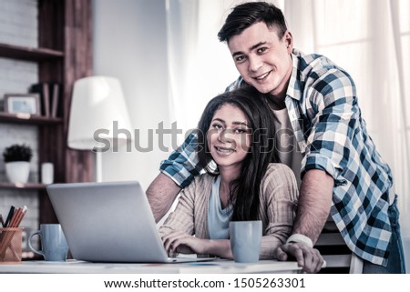 International couple. Mixed race young lady sitting on the chair with her boyfriend overtopping her in supporting gesture