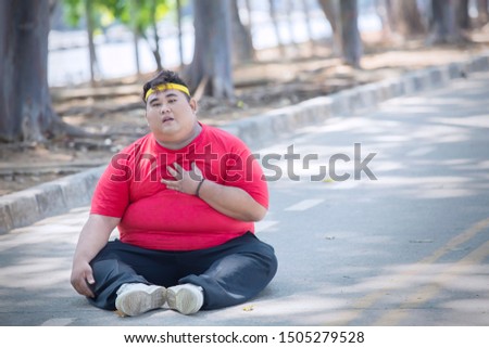 Picture of overweight man having heart pain after exercising while sitting in the park