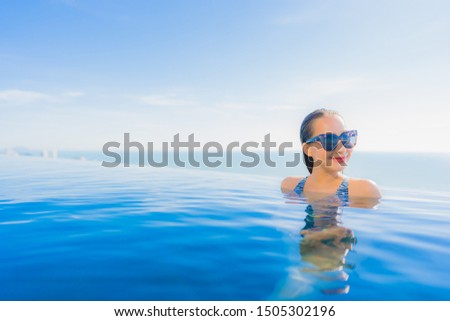 Portrait beautiful young asian woman smile happy relax around swimming pool in hotel resort with sea and ocean view for leisure travel in holiday vacation