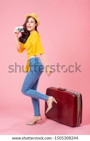 Smiling woman traveler holding camera and luggage in holiday on pink backgrounds, relaxation concept, travel concept