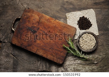 Cutting Board, rosemary and spices on a old wooden table Royalty-Free Stock Photo #150531992