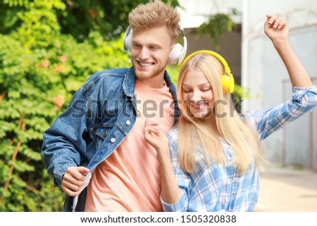 Young couple listening to music outdoors