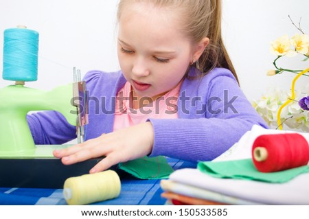 Cute little girl sewing on a sewing machine at home