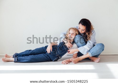 Mom and daughter in jeans cuddle laughing