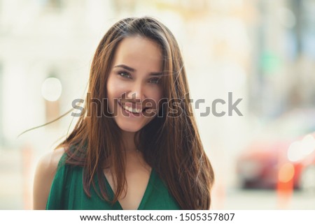 Young pretty likable cheerful woman posing summer city outdoor. Beautiful self-confident girl dressed in emerald-colored jumpsuit with long brown hair walking street enjoing her life, urban lifestyle Royalty-Free Stock Photo #1505357807