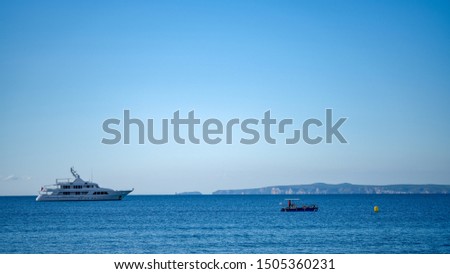 Big luxury yacht anchoring in calm water in a sunny day in the Mediterranean on the background of the islands and blue sky. Water activities, vacation at sea, happy holidays.