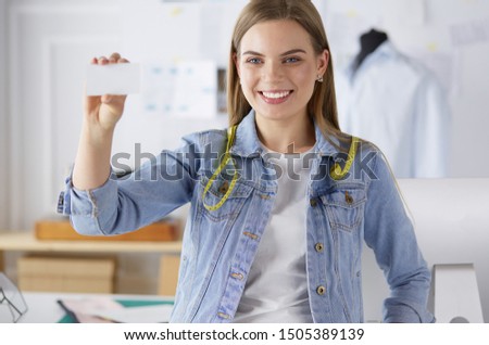 Beautiful young designer with business card in office