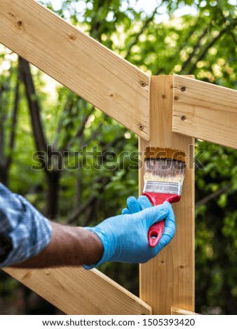 Adult craftsman carpenter with the brush painting the boards of a wooden fence. Housework, do it yourself. Stock Photography.