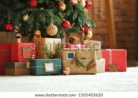 Beautiful Christmas gifts under fir tree on floor in room Royalty-Free Stock Photo #1505403620