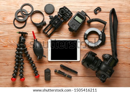 Modern tablet computer with photographer's equipment on wooden background
