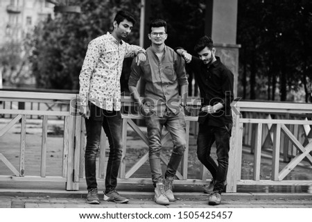 Three indian guys students friends walking on street. Black and white photo.