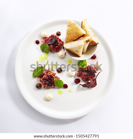 Beef Tartar sauce and toasted bread top view. French dish with anchovy sauce isolated on white background. Prepared restaurant gourmet meal concept. France traditional cuisine. Served food composition