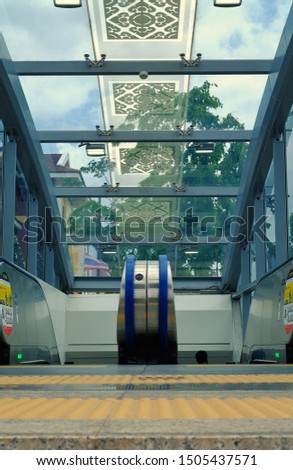 A escalator to an underground train station below with glass roof. 
