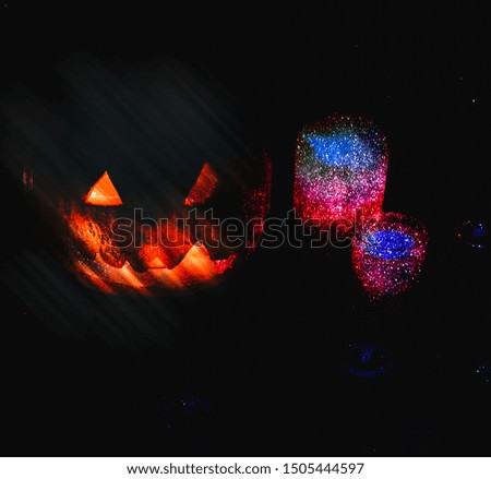 Halloween pumpkin in the darkness. Lights lamps and candles with violet sparkles. Art image. Mystical autumn holiday. Festive details. Trick-or-treat tradition. All Saints day in October.