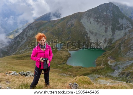 Backpacker lady with camera hiking on a mountain trail